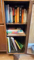 Cabinet with three shelves of assorted books and music booklets