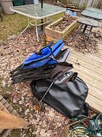 Two folded camp chairs, blue and dark, stacked with stove case visible