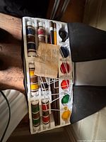 Full view of croquet set in styrofoam tray showing mallet heads, handles, balls, wickets and case