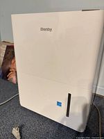 Front view of white Danby dehumidifier with water level window and cord