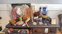 Overall view of lot on tabletop showing elephants, lamp, powder horn, parrot, additional décor