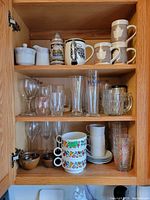 Overall cabinet view showing glassware, mugs, bowls, plates