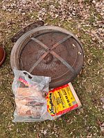Top view of round steel fire pit with mesh screen and kindling bags