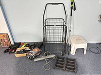 Overview of all items on floor including cart, stool, walking stick, battery charger, cables, traction boards, strap