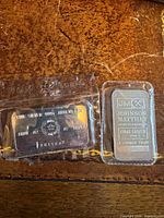 Front of both silver bars showing branding, weight, purity, serial numbers