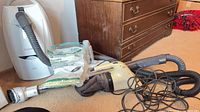 Kenmore Elegance vacuum, Dirtbuster vacuum, two sealed bag packs, cords and hose on floor
