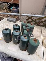 Nine green 1-lb propane cylinders on outdoor table