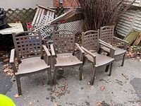Four brown plastic patio chairs outdoors