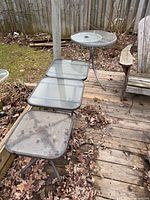 Three square glass-top side tables and one round glass-top side table on deck