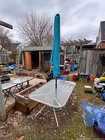 Full view of glass patio table with umbrella and stand in yard