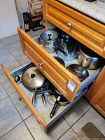 Drawer containing multiple pots, pans, lids, steamer basket