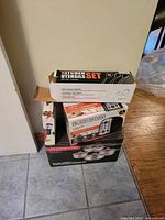 Stacked view of boxed cookware set, Black+Decker toaster, utensil set