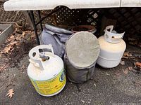 Two propane cylinders and two covers under table
