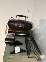 Group view of boombox, cassette tapes, carrying case and record racks