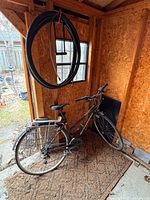 Full view of bicycle inside shed with spare tires hanging above