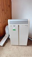Front view of Sharp portable air conditioner with hose and window panel visible