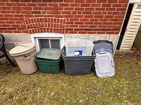 Group of outdoor plastic containers lined against brick wall
