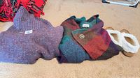 Sweater, poncho and slippers laid out on carpet