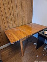 Overall view of wooden table against wall with leaf inserted