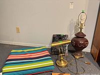 Group view of cushion, brass desk lamp, terra cotta art panel, ceramic lamp base and kaleidoscope