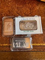 Front view of all three 1 oz silver bars: Aquarius, Silver Bull in case, Christmas Joy '86