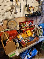 Workbench with two red metal toolboxes, DeWalt and Mastercraft drill bit sets, caulking guns, tubes of caulk, hand tools and hardware