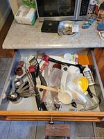 Open drawer with assorted utensils and tools visible