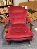 Front view of burgundy velveteen armchair with wood arms and legs