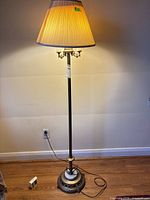 Full view of metal floor lamp, base to shade, cord visible