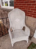 Front view of white wicker chair showing high back and arms