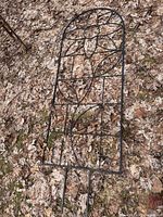 Full view of arched metal garden trellis lying on ground