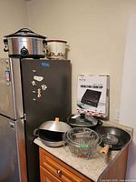 Overall lot showing cooktop box, woks, slow cookers, basket and utensils