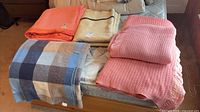 Five folded wool blankets laid on bed