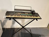 Full view of Yamaha PSR-48 keyboard on X-stand with music rest and power adapter