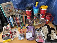 Overview of lot showing tumblers, DVDs, figurines, bags, pouches and accessories
