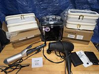 Group view of two Songmics makeup cases in boxes, black hair dryer, silver curling iron, black clear plastic container, two small pouches