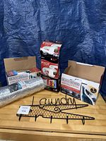 All items grouped on table: steam iron box, two vent kit boxes, foil duct roll, metal laundry rack