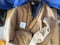 Brown Carhartt canvas coat laid flat, sleeves crossed