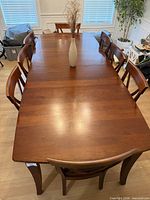 Top view of rectangular cherry-finish dining table with vase and eight chairs