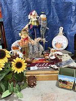 lot overview showing scarecrows, sign, textiles, doormat, planter boxes, sunflower arrangement, vase