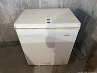 Front view of white Haier chest freezer with lid closed and power cord visible