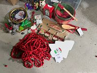 Group view of red bead garland, ornaments, cookie tin, sign, utensils, foam trees, gift tags, hooks