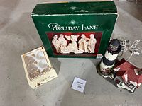 Lot overview showing boxed Holiday Lane nativity, boxed glass ornaments, ceramic lighthouse decoration