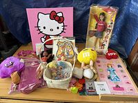 Overall lot showing Barbie doll, Hello Kitty panel, plush toys, basket with figures, magnetic dress-up set