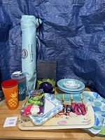 Overall lot view showing trays, plates, tumblers, balloons pack, beach bag, speaker box