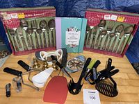 Full view of lot showing both boxed flatware sets, meal planner book, candlesticks and assorted utensils