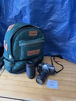 Full view of backpack, camera with mounted lens and separate telephoto lens