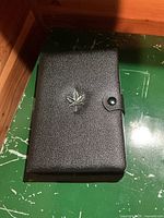 Closed black textured case with embossed maple leaf