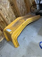 Side view of yellow steel auto ramp showing curves and wear