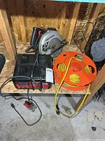 Battery charger, circular saw and cord reel on shelf